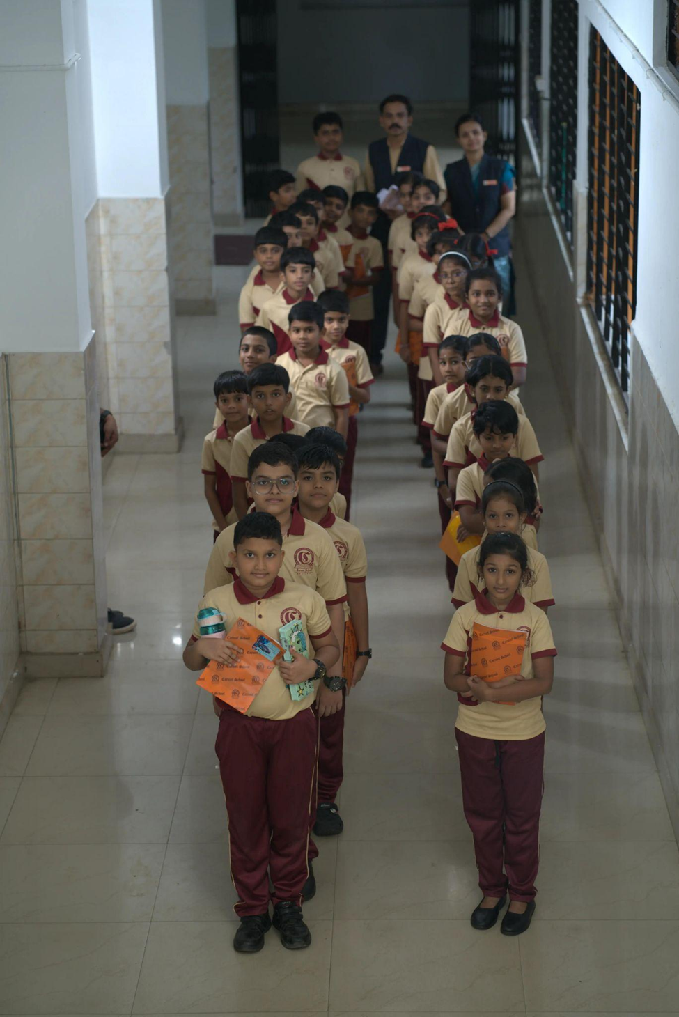 Students standing in a corridor with teachers in the background